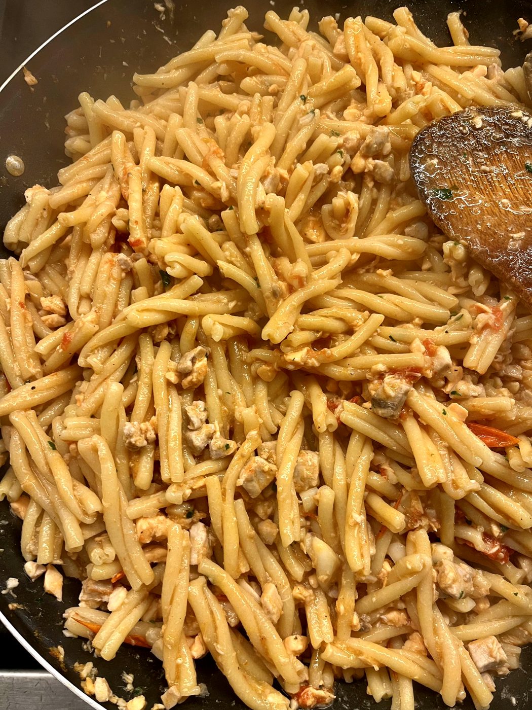 Casarecce in a pan with a wooden spoon