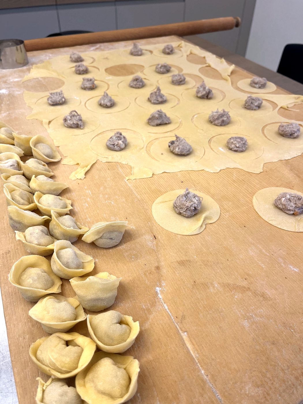 Tortellini being shaped on a pastry board