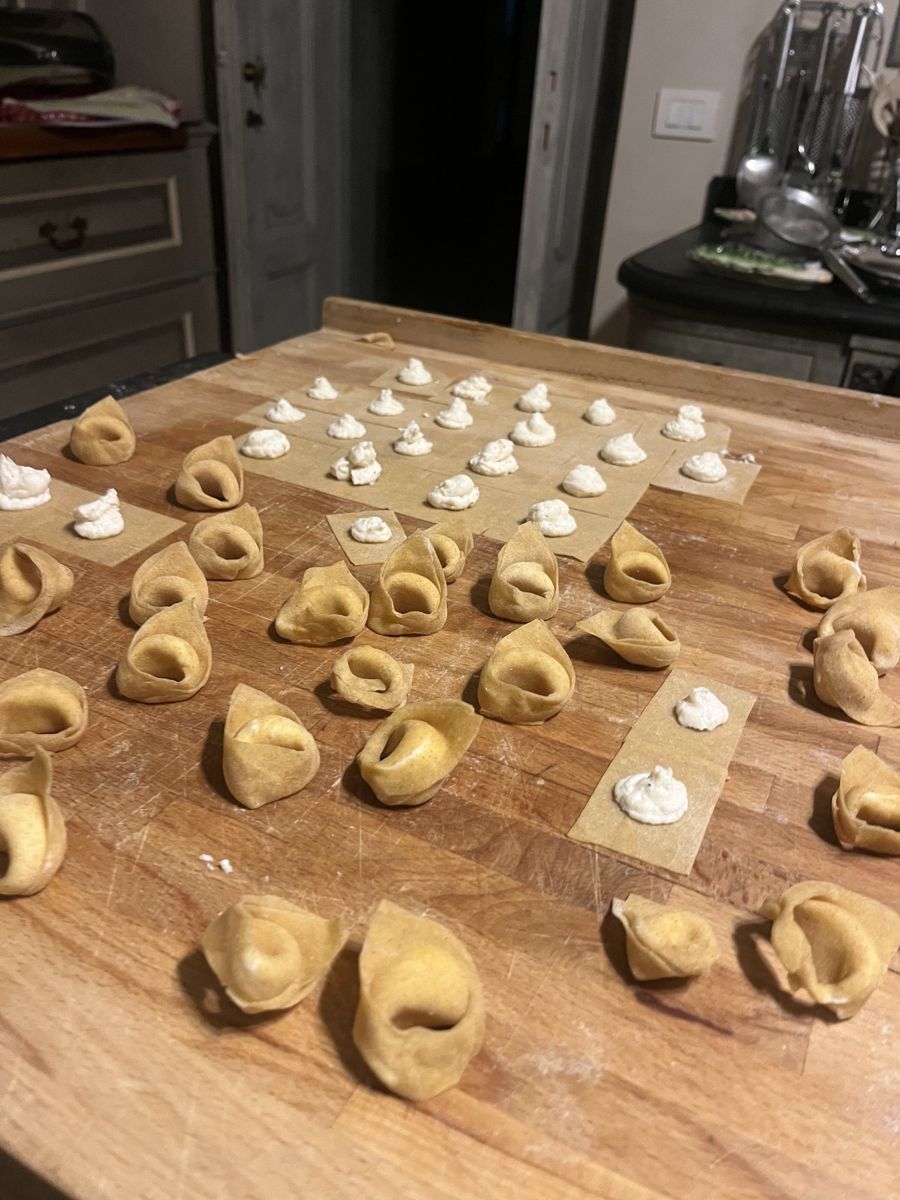 Tortellini being shaped by hand on a pastry board